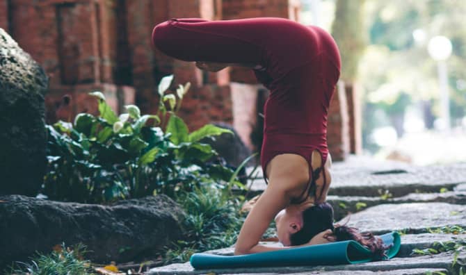 Woman in red outfit doing a headstand crossed leged