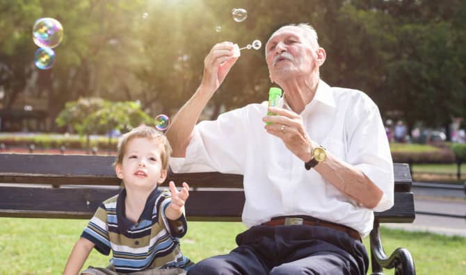 A young boy and an old man blowing bubbles.