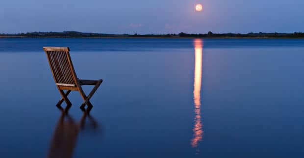 Wooden chair on a lake looking at the sunset