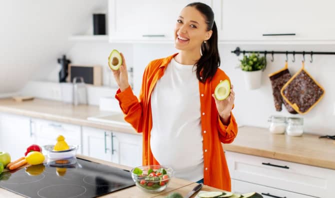 A pregnant woman eating a healthy salad with avocado.