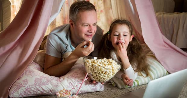 Father and daughter enjoying a dog-themed movie together.