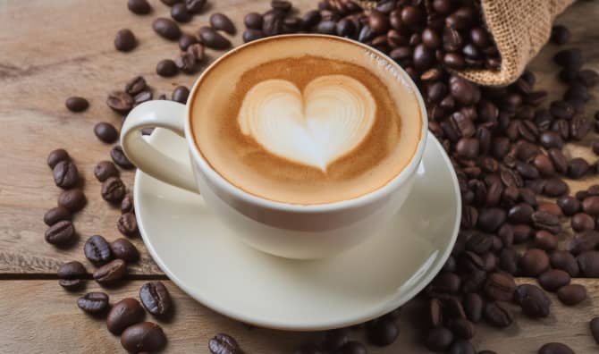Cup of coffee latte with heart shape and coffee beans.