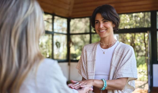On woman smiles at another.
