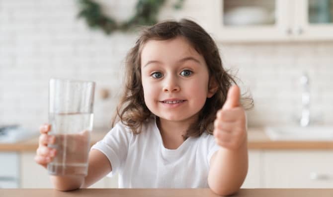 A cute girl enjoying a glass of fresh water.