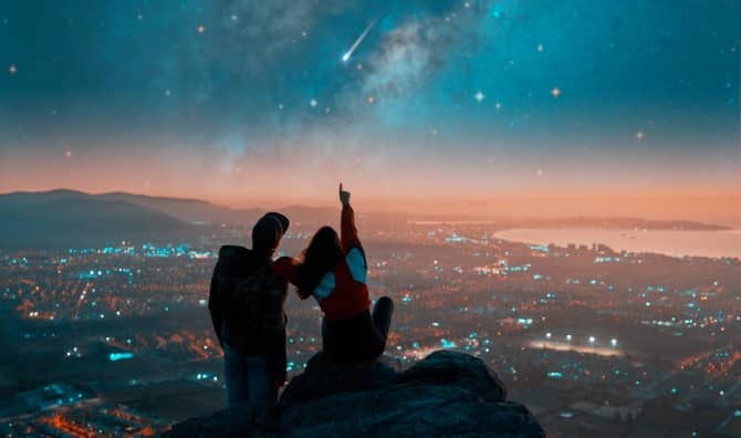 Couple watching shooting stars from a rooftop.