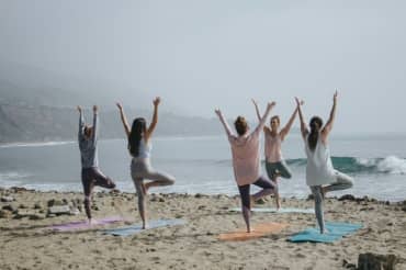 Women doing yoga on the beach.