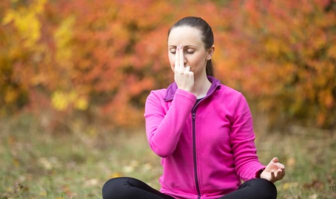 Woman practicing alternate nostril breathing.