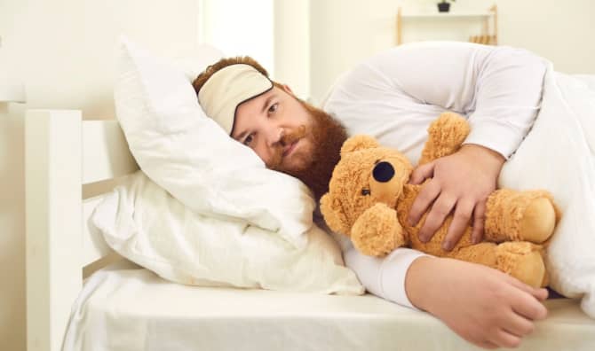 Adult man sleeping with a stuffed animal.