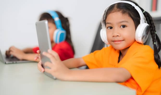Two young students wear headphones.