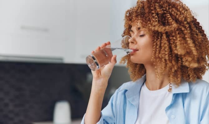 A woman drinks water from a glass.