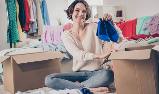 A woman holds up a pair of shoes.