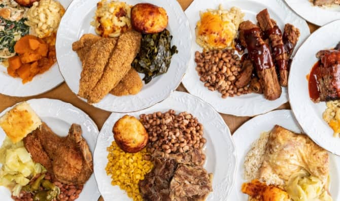 A soul food feast with a variety of dishes served on numerous plates.