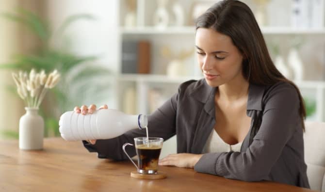 Woman adding milk to her coffee.