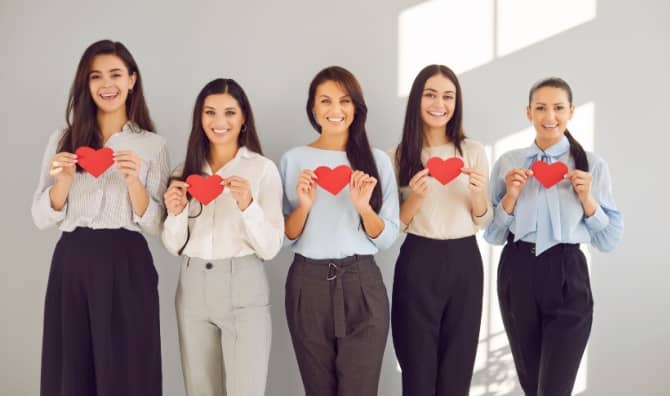 Women hold red paper hearts.