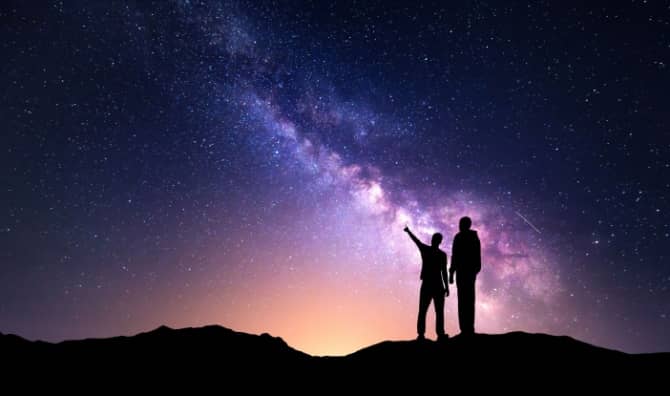 A silhouette of a family with a backdrop of the milky way.