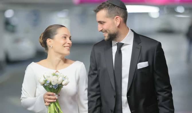 A couple holds hands on their wedding day in an underground shelter.