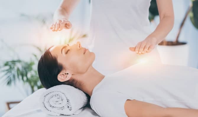 A calm woman receives reiki healing therapy.
