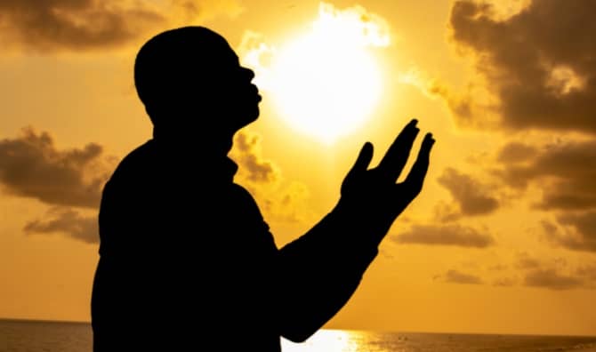 A man silhouetted against a colorful sunset.