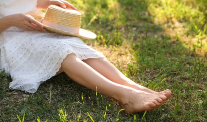 A woman sitting barefoot outdoors.