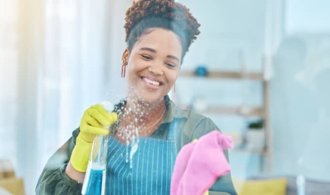 A smiling woman cleans a hospital window.