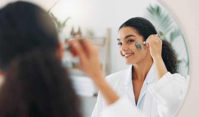 A happy woman using a face roller.
