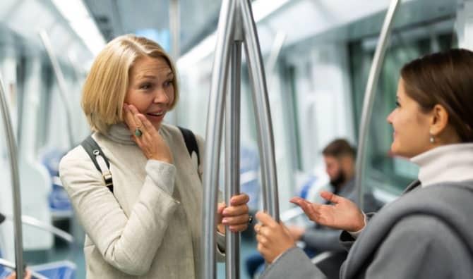 A woman talking with a fellow traveler in a subway car.