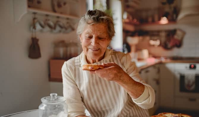 A grandmother eating a pastry.