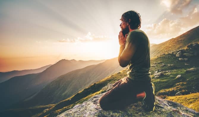 A man sits at sunset in the mountains.