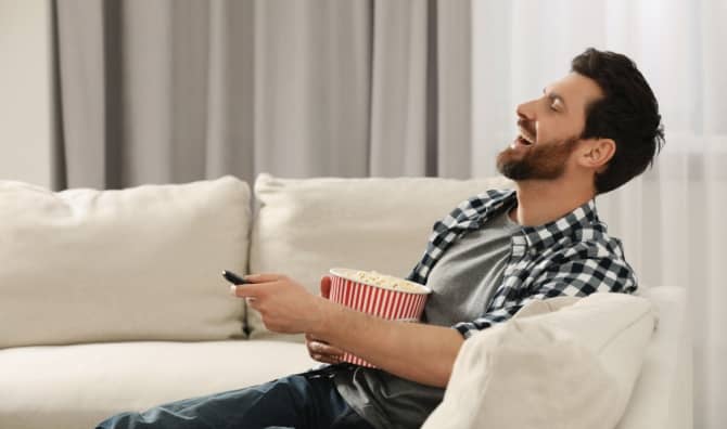 A man laughs while watching TV.
