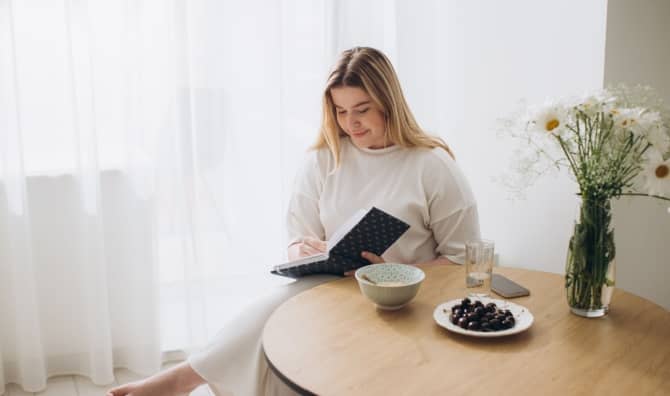A woman sits and writes in a journal.