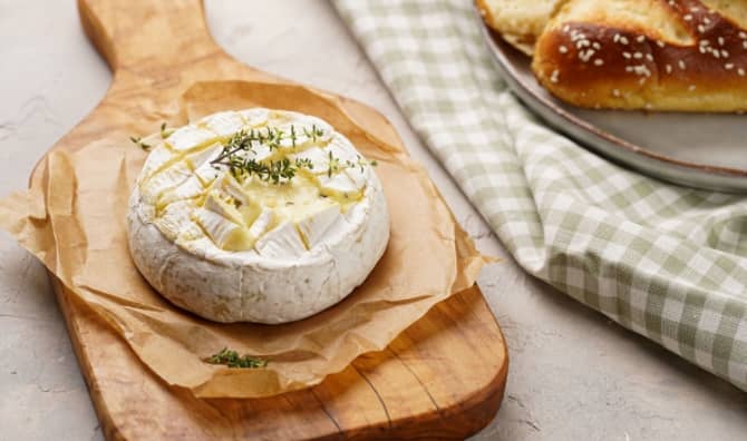 Oven baked camembert cheese on wooden board.