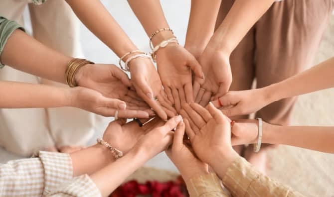 Young girls stand in a circle with their hands together.