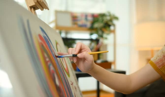 A close up of a female artist painting abstract artwork.