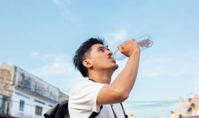 Young man drinking water from a plastic bottle.