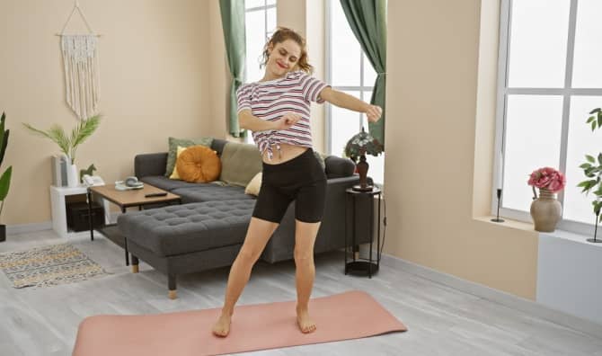 A young woman dances in her living room.