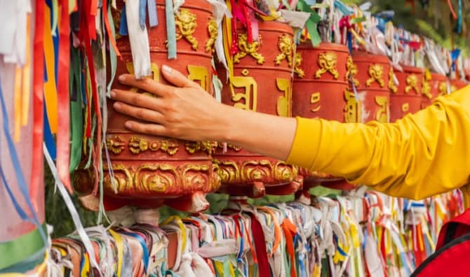 A pilgrim touches a turning spinning Buddhist prayer wheel.