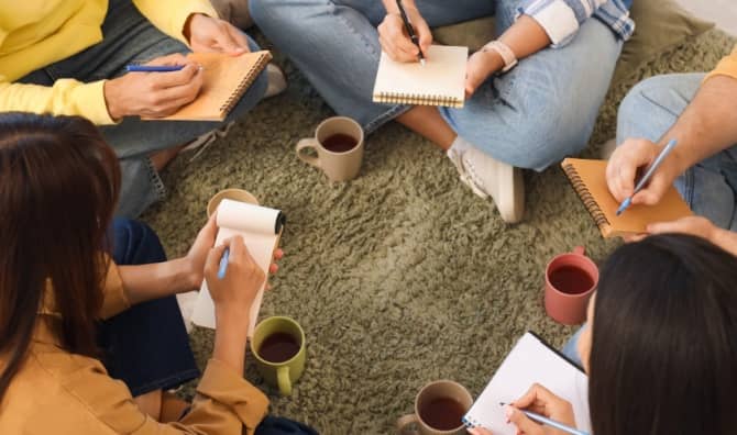 Young people write in notebooks.