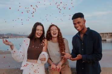 Cheerful young friends photographed by the sea, enjoying life.