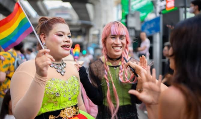 People smiling during a Pride Month parade.