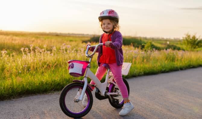 A little girl in a helmet sits on her bicycle.