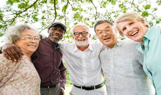 A group of diverse elderly friends smiling outdoors.
