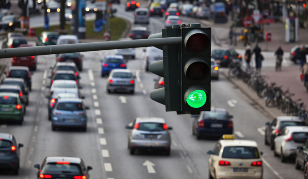 Green traffic light showing go signal with a busy street full of cars blurred in the background