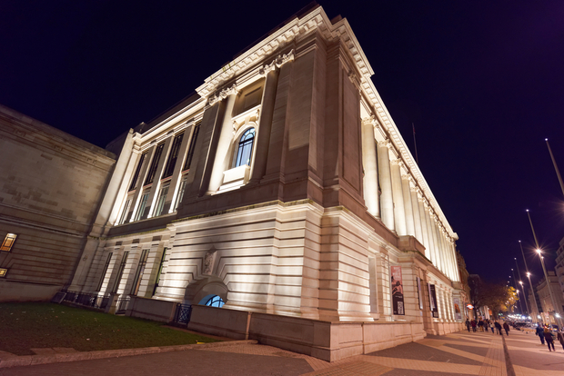 Imperial College at night, Classical stone building with columns illuminated by warm lighting at night against a dark sky.