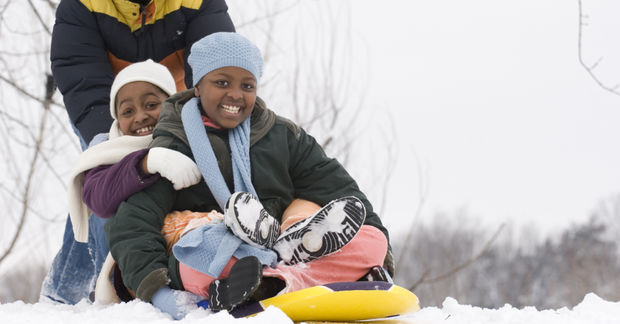 Children sledding together in snow.