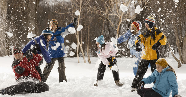 Group snowball fight in winter forest.