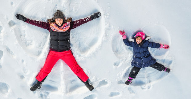 Two children making snow angels in snow.