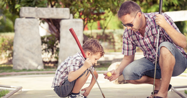 photo Father teaching son to play baseball outdoors.