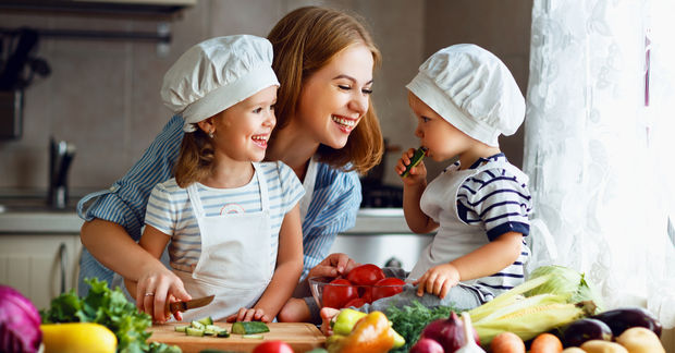 Mom with 2 kids cutting vegetables in the kitchen
