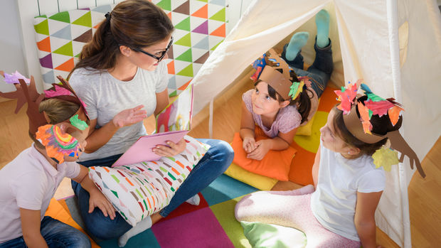 young woman telling a story to three kids