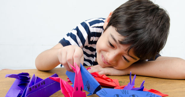 young kid playing with origami